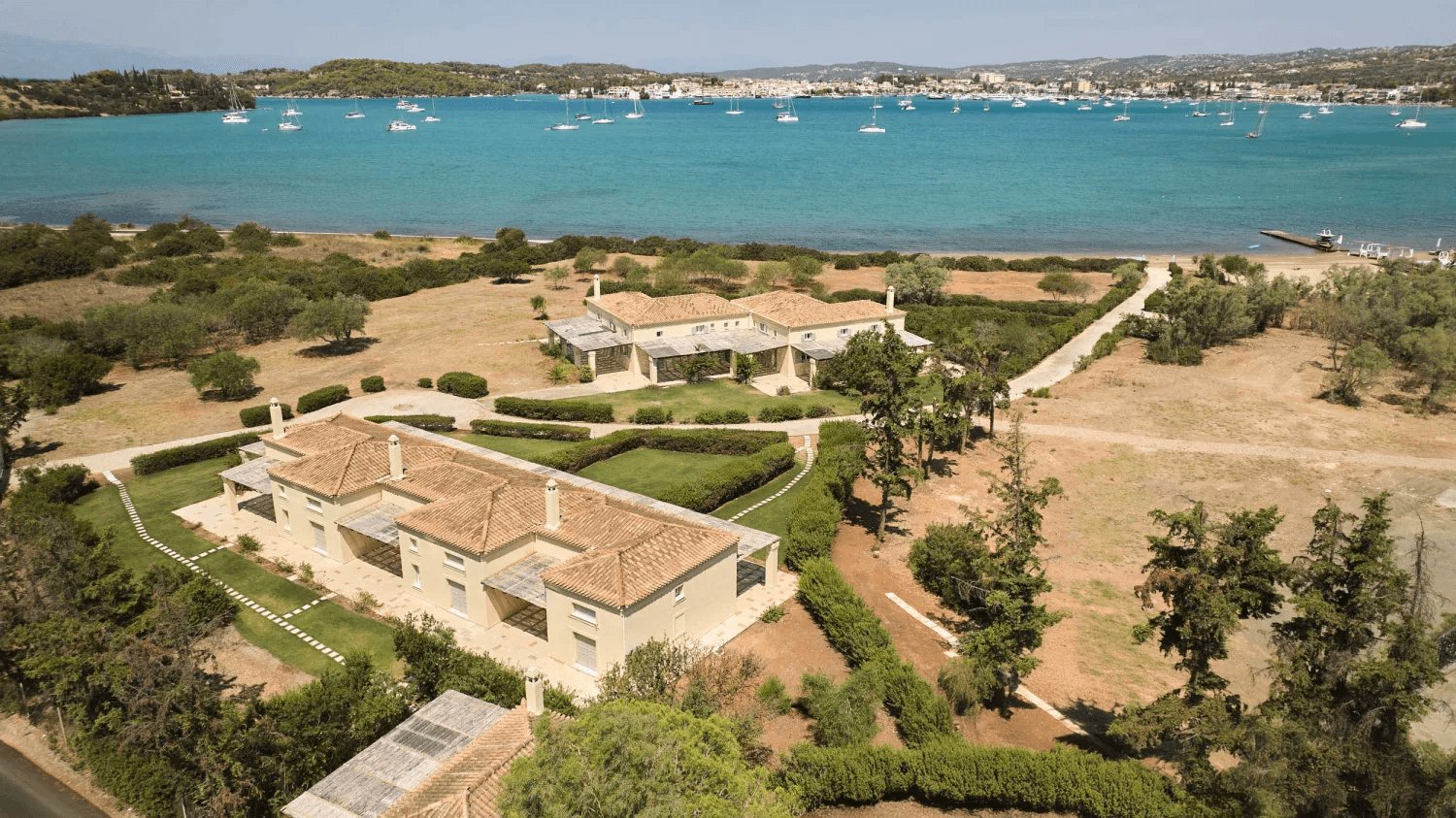 Stunning aerial perspective of a grand villa with a vast yard, beautifully situated by the vibrant blue sea