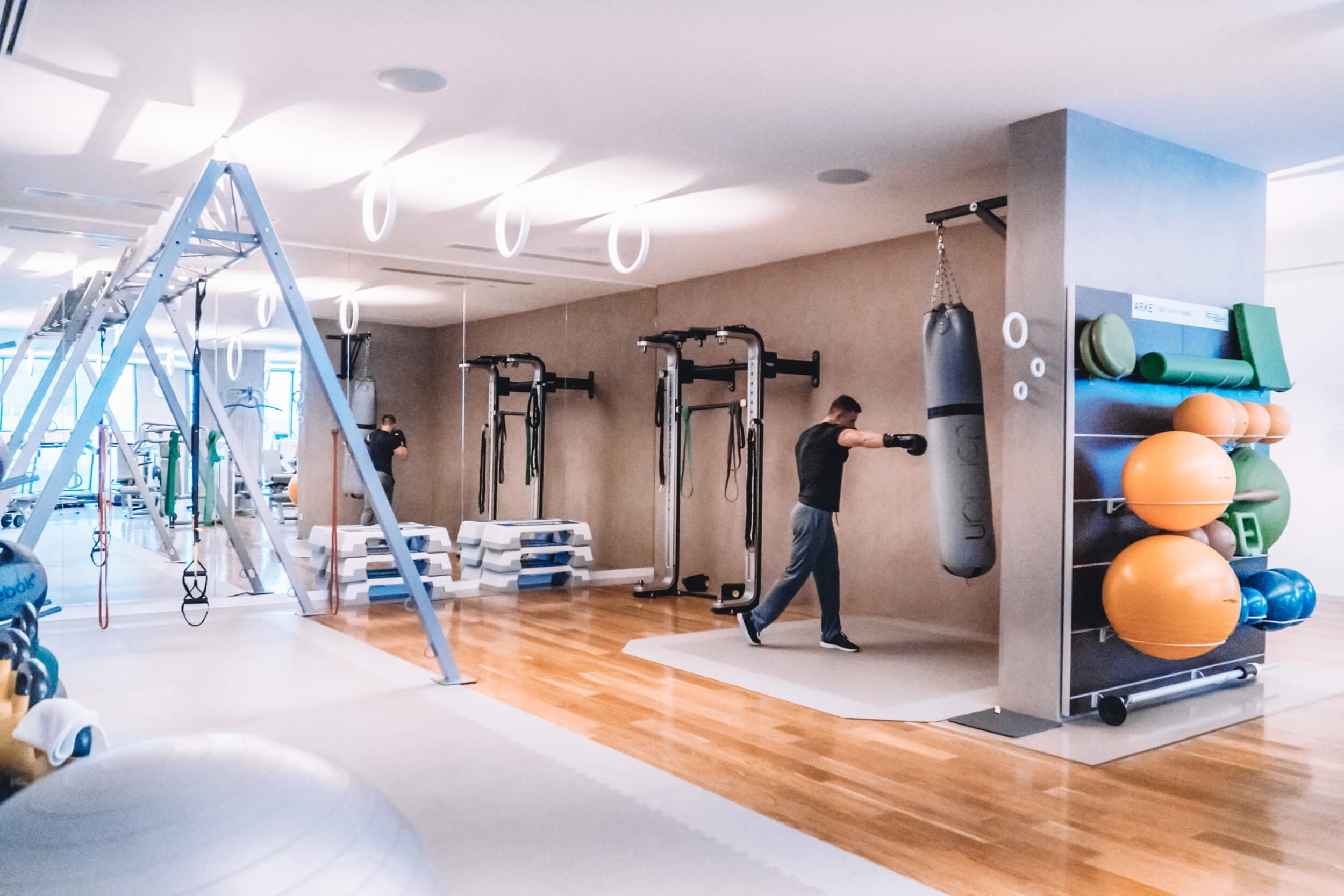 An image of tony gym. A man is punching a punchbag. Gym equipment is seen around the room