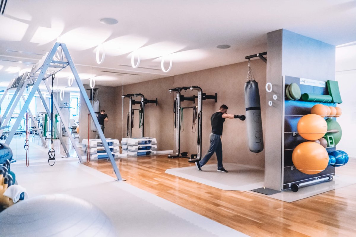 An image of tony gym. A man is punching a punchbag. Gym equipment is seen around the room