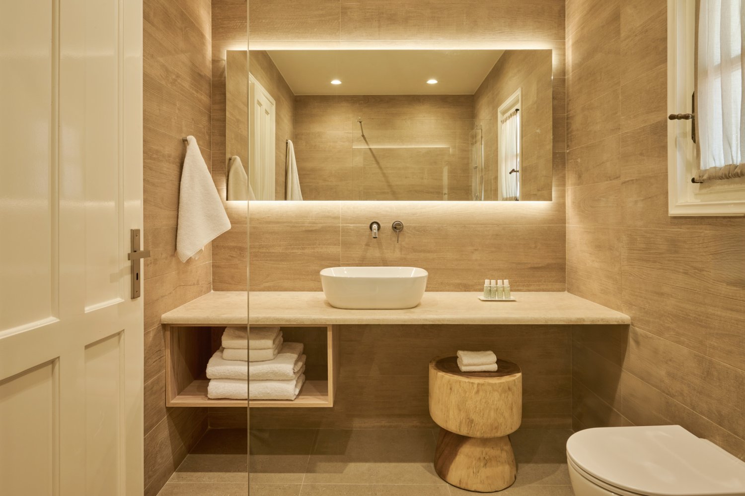 A serene bathroom featuring a stylish sink, elegant toilet, and a large mirror, perfect for a tranquil retreat